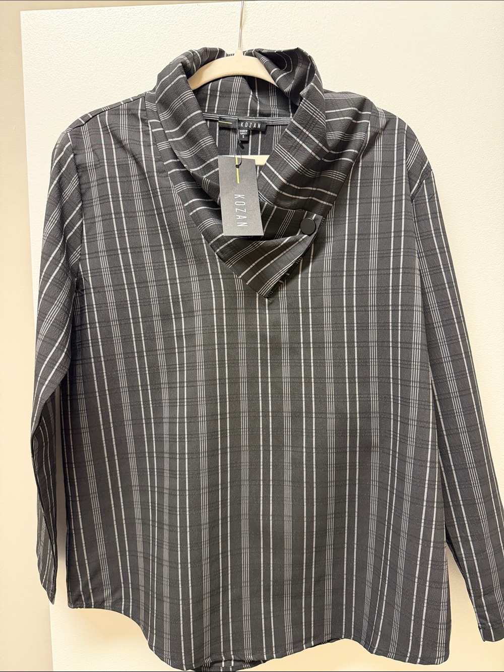 This Kozan striped top features a stylish asymmetric folded collar with button